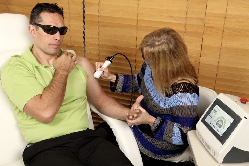 physiotherapist giving a man laser therapy