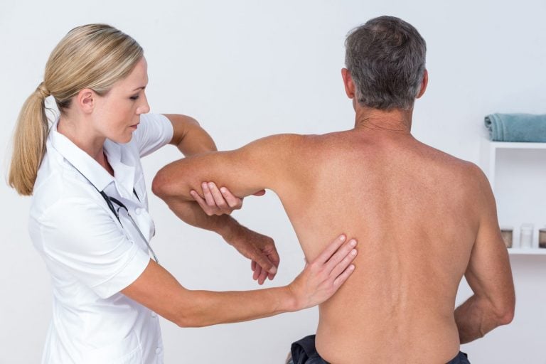 physiotherapist manipulating a mans shoulder