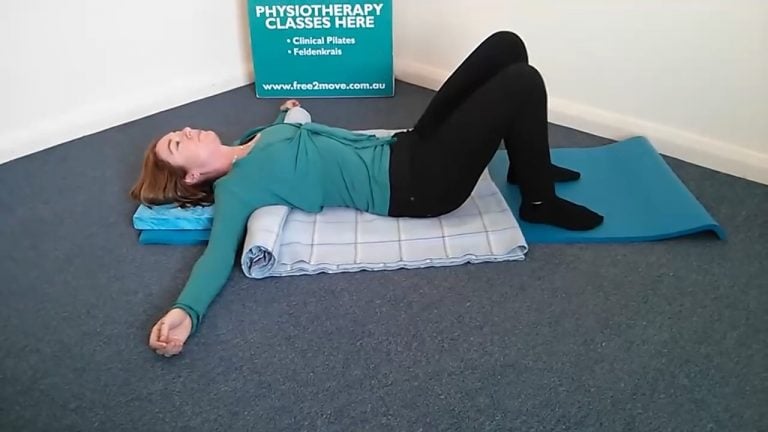 Jodie Krantz on her back on a rolled up blanket under her back and head cushion in the Free2move pilates studio feet on the ground arms out wide