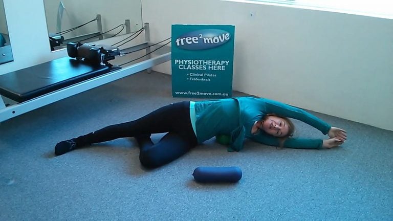 Jodie Krantz in the Free2move Pilates studio doing a side stretch with a mini-ball under her hip