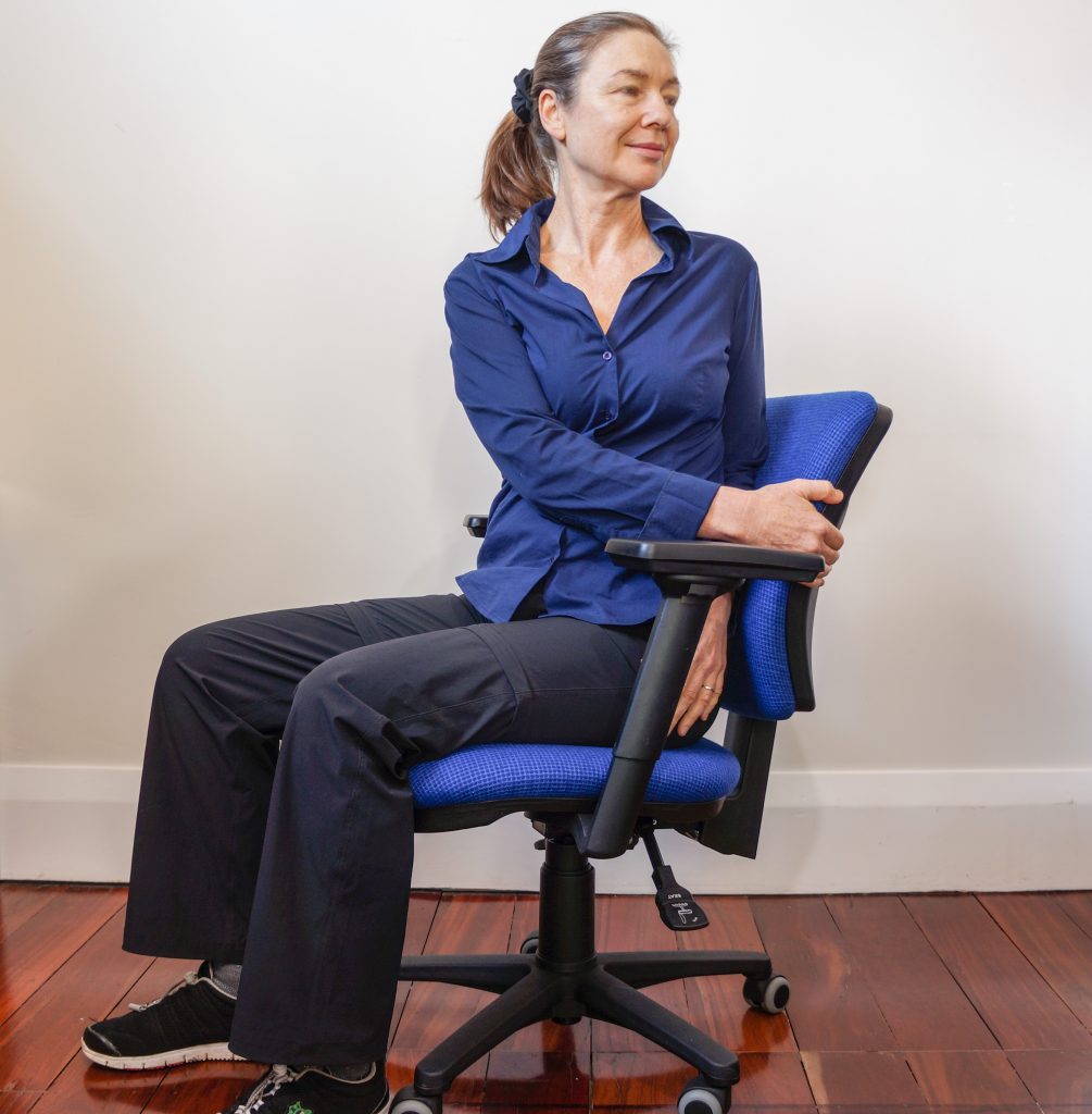woman sitting in office chair wisting round to the left looking behind